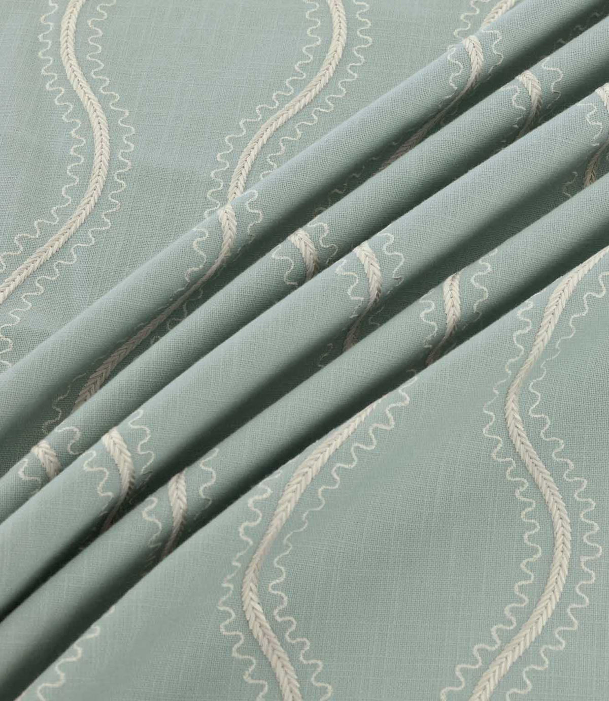 Riverhead Saltwater embroidered fabric gathered into soft folds, showcasing raised ivory wavy stripes, delicate scalloped edges and a muted seafoam blue-green base.