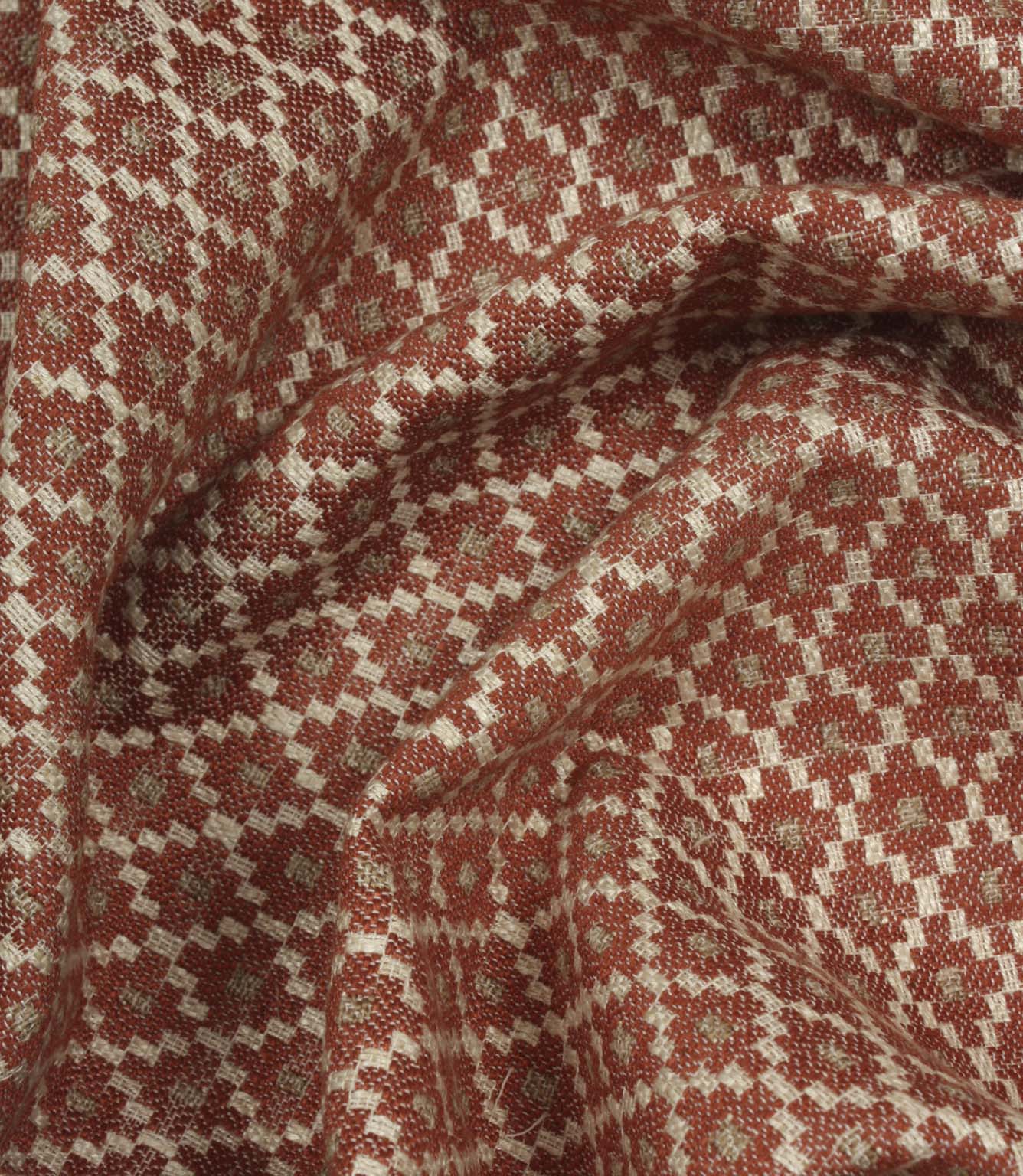 Draped geometric upholstery fabric with a soft woven handle and intricate rust red and cream lattice-inspired pattern.