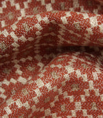 Macro close-up of woven fabric highlighting the textured surface, detailed geometric weave, and warm earthy colour palette.
