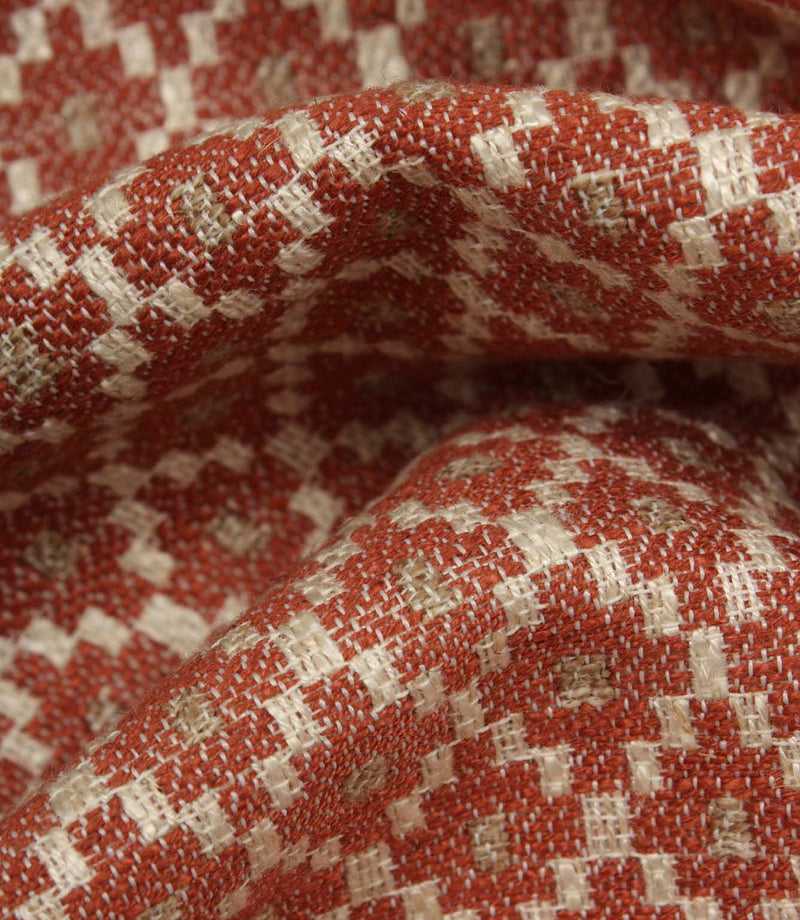 Macro close-up of woven fabric highlighting the textured surface, detailed geometric weave, and warm earthy colour palette.