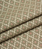 Folded patterned fabric showing the detailed woven texture and repeating geometric motif in sage green, cream, and blush pink tones.