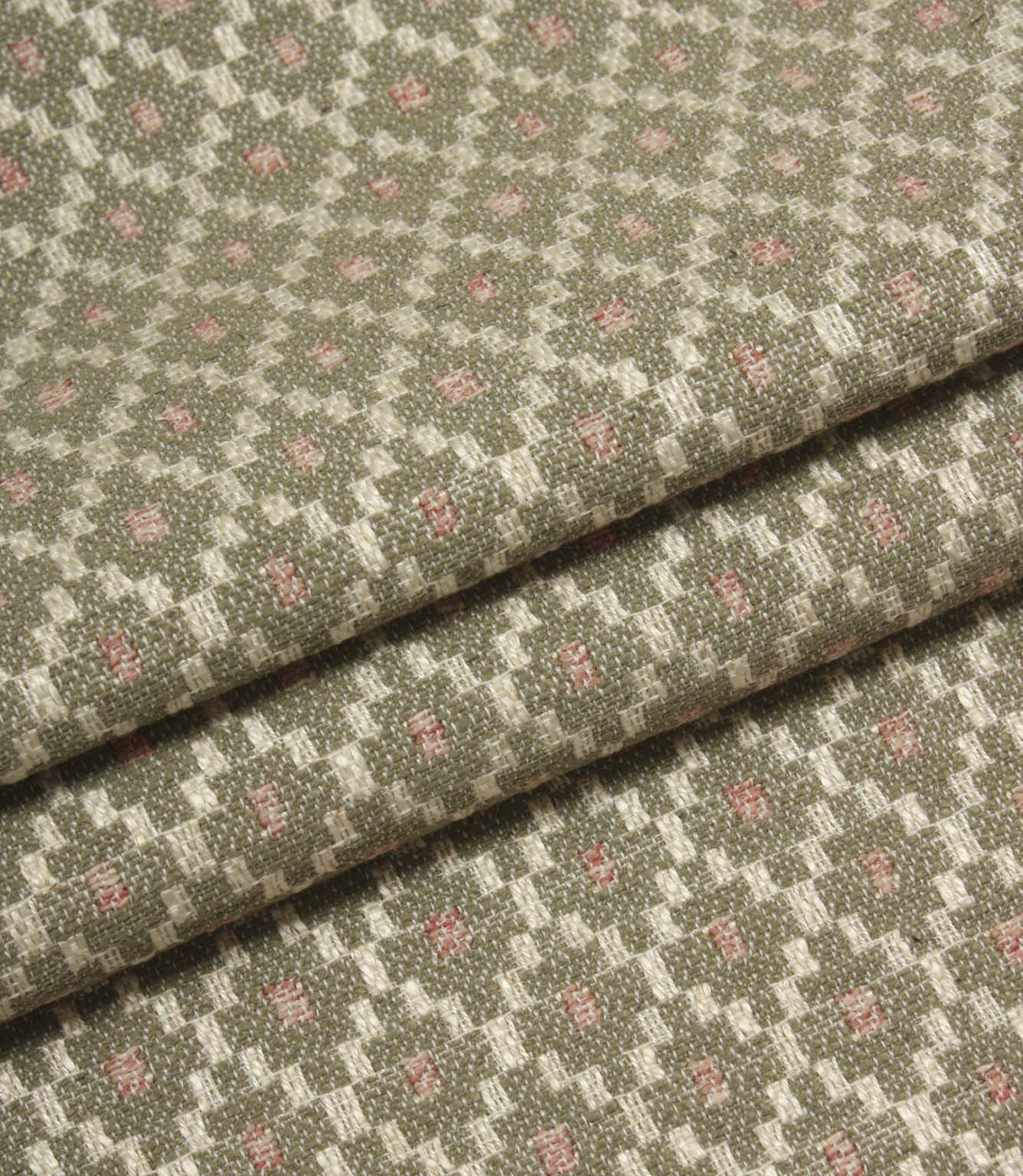 Folded patterned fabric showing the detailed woven texture and repeating geometric motif in sage green, cream, and blush pink tones.