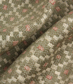 Macro close-up of woven fabric highlighting the textured surface, detailed geometric weave, and subtle sage green and blush pink colour palette.