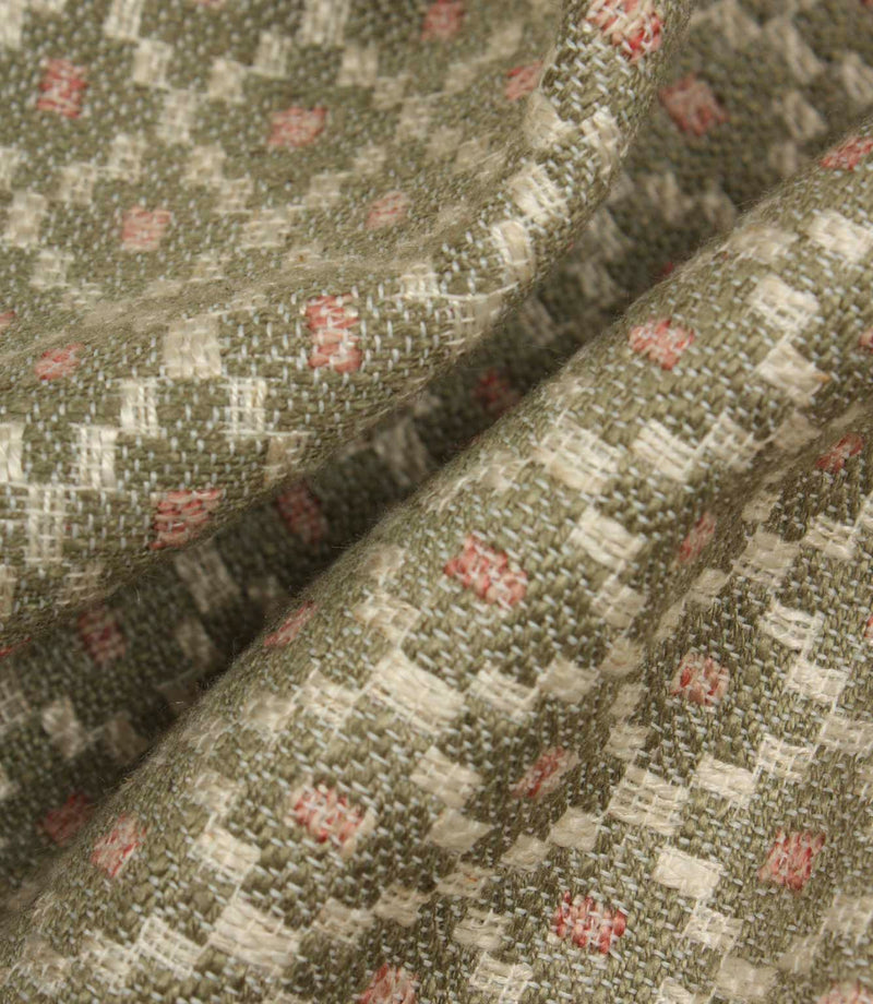 Macro close-up of woven fabric highlighting the textured surface, detailed geometric weave, and subtle sage green and blush pink colour palette.