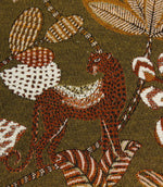 Close-up of woven leopard motif on olive green decorative fabric with textured botanical detailing.