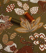 Olive green animal print upholstery fabric with embroidered-effect leaves and flowers, shown with matching thread reels.