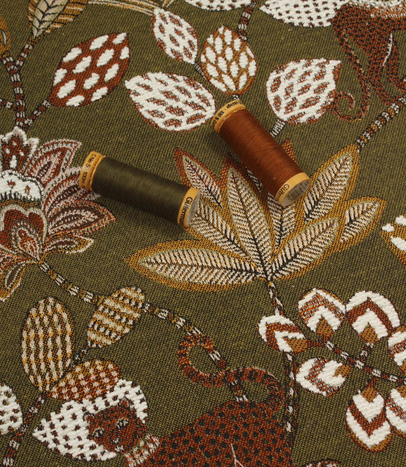 Olive green animal print upholstery fabric with embroidered-effect leaves and flowers, shown with matching thread reels.