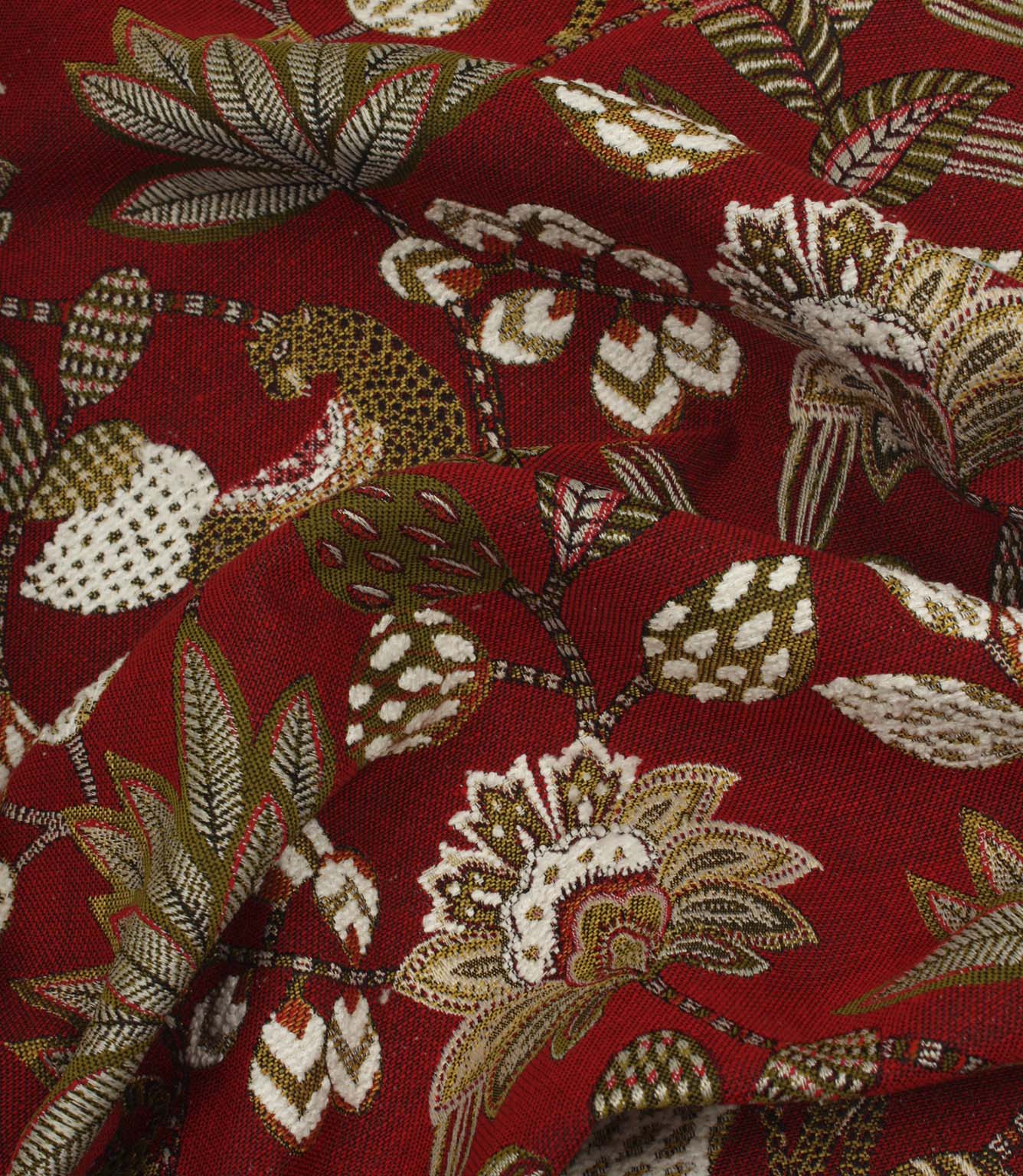 Draped red jacquard fabric with decorative jungle-inspired animal and floral pattern.