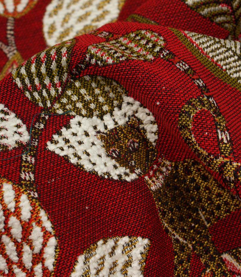 Detailed close-up of textured woven botanical fabric in red, cream and olive tones.