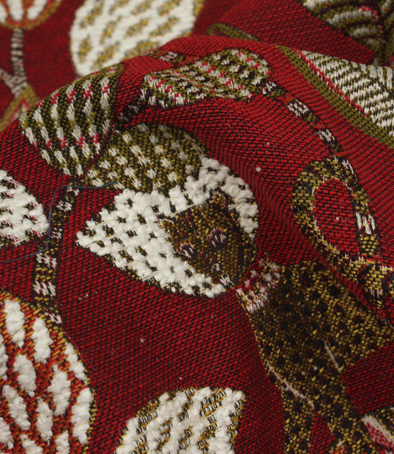 Detailed close-up of textured woven botanical fabric in red, cream and olive tones.
