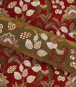 Rolled olive green leopard print fabric displayed against coordinating red botanical fabric backdrop.