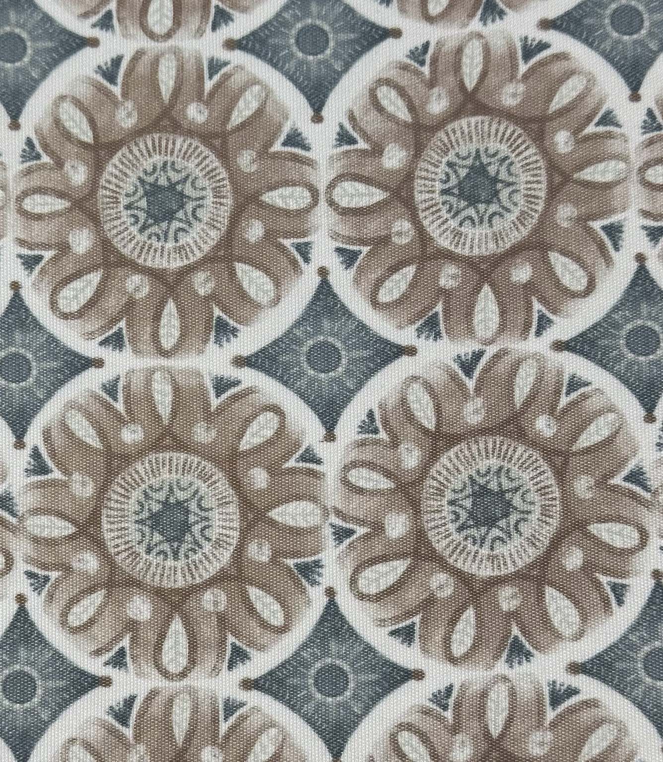Close-up of Sand Rosette foliage outdoor fabric with stylised floral motifs in warm beige and dusty blue tones against a soft cream background.

