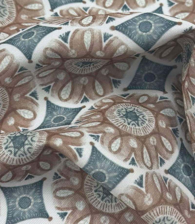 Draped Sand Rosette outdoor fabric showing a vintage-inspired floral and geometric pattern in muted teal, taupe, ivory, and grey shades.