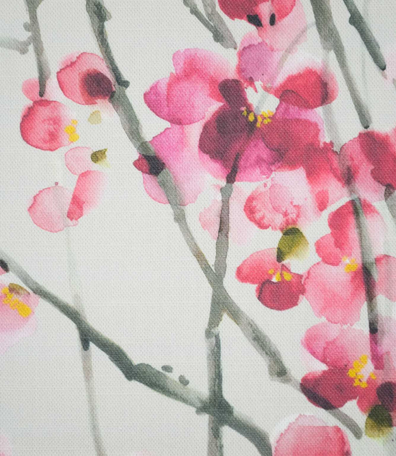 Close-up of Seville Blossom Stone fabric showing detailed pink and raspberry blossom petals with small yellow centres, delicate grey-green branches and a fine woven texture.