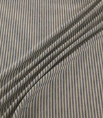 Shoreham Nautica fabric draped in soft diagonal folds, showcasing its narrow navy blue and cream ticking stripes, textured woven finish and natural drape.