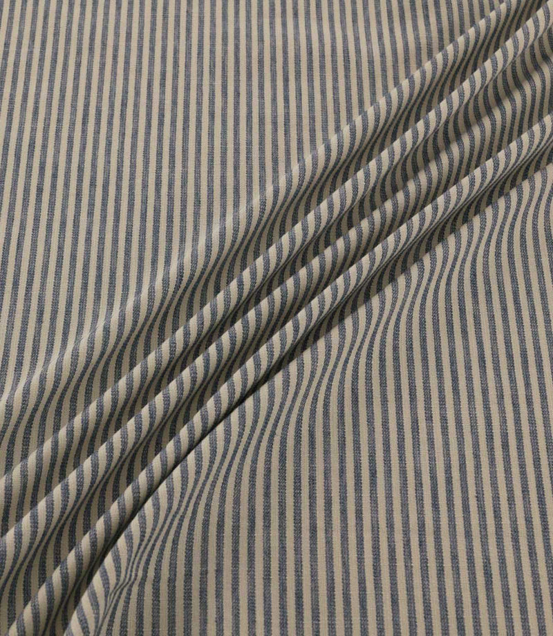 Shoreham Nautica fabric draped in soft diagonal folds, showcasing its narrow navy blue and cream ticking stripes, textured woven finish and natural drape.