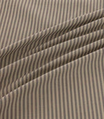 Shoreham Rockport striped fabric arranged in soft diagonal folds, showcasing its alternating taupe grey and natural beige ticking stripes, textured woven finish and gentle drape.