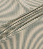 Shoreham Saltwater fabric arranged in soft diagonal folds, showcasing its delicate blue-grey and natural cream vertical stripes, textured woven finish and natural drape.