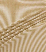 Shoreham Sandytan striped fabric arranged in soft diagonal folds, showcasing its warm sandy beige and cream ticking stripes, textured woven finish and natural drape.