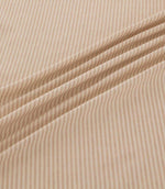 Shoreham Shell striped fabric arranged in soft diagonal folds, showcasing its delicate blush pink and cream ticking stripes, textured woven finish and natural drape.