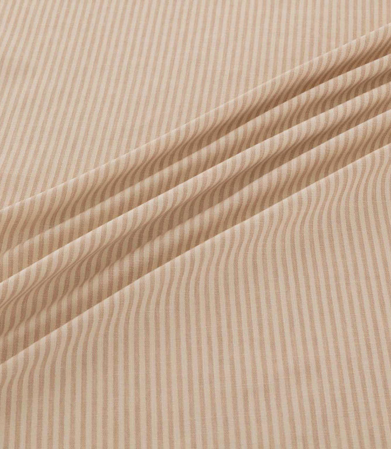 Shoreham Shell striped fabric arranged in soft diagonal folds, showcasing its delicate blush pink and cream ticking stripes, textured woven finish and natural drape.