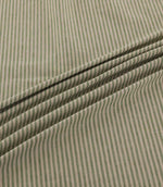 Shoreham Spring fabric arranged in soft, diagonal folds, showcasing its delicate sage green and natural beige vertical stripes, textured woven surface and gentle drape.
