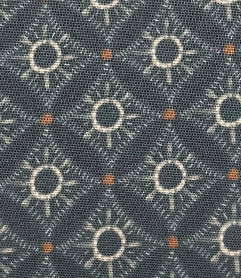 Close-up of Solstice Halo foliage-inspired outdoor fabric with abstract halo motifs in soft blue-grey, cream, and warm amber tones.