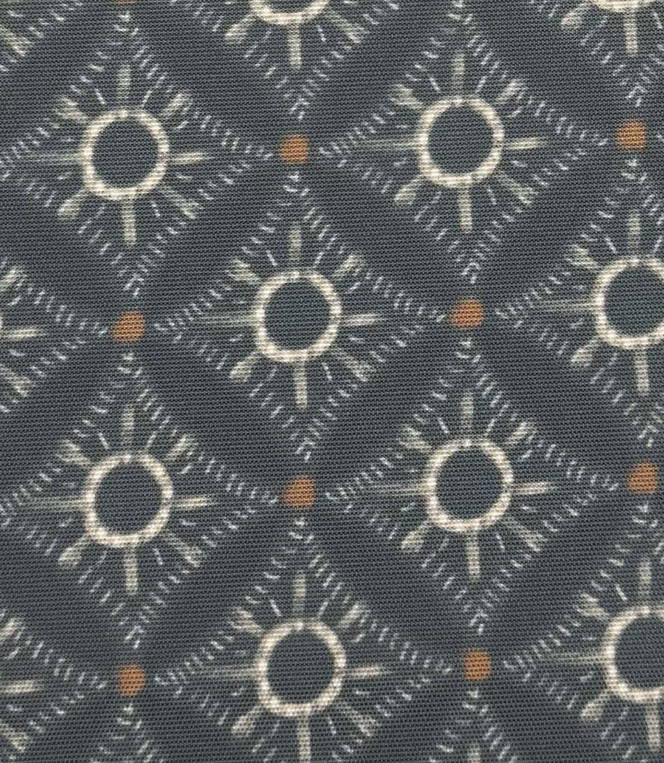 Close-up of Solstice Halo foliage-inspired outdoor fabric with abstract halo motifs in soft blue-grey, cream, and warm amber tones.