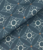 Folded Solstice Halo outdoor fabric featuring ivory geometric sunburst motifs on a muted blue background with small rust accents.