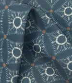 Draped Solstice Halo outdoor fabric showing a textured geometric pattern in dusty blue, ivory, and burnt orange shades.