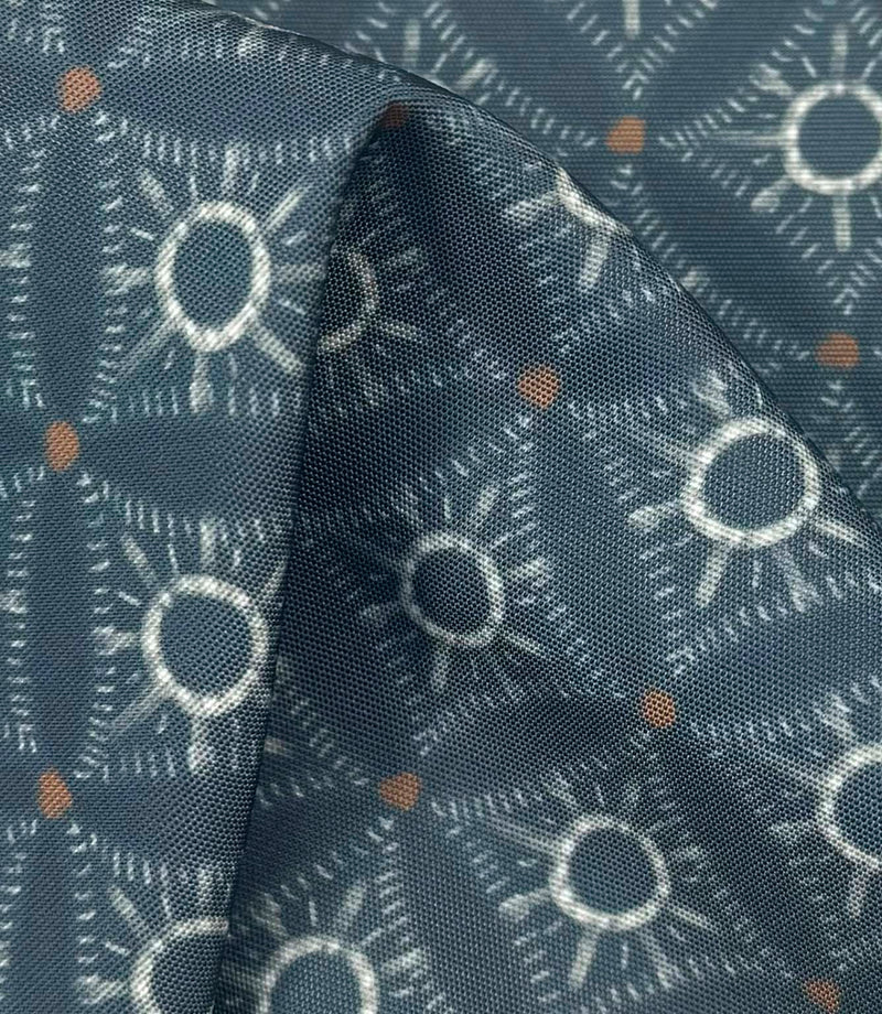 Draped Solstice Halo outdoor fabric showing a textured geometric pattern in dusty blue, ivory, and burnt orange shades.