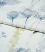 Sorong Lemon fabric arranged in a soft fold, showing pale blue watercolour flowers on slender stems alongside delicate yellow-green foliage and lavender botanical details.