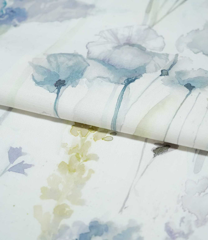 Sorong Lemon fabric arranged in a soft fold, showing pale blue watercolour flowers on slender stems alongside delicate yellow-green foliage and lavender botanical details.