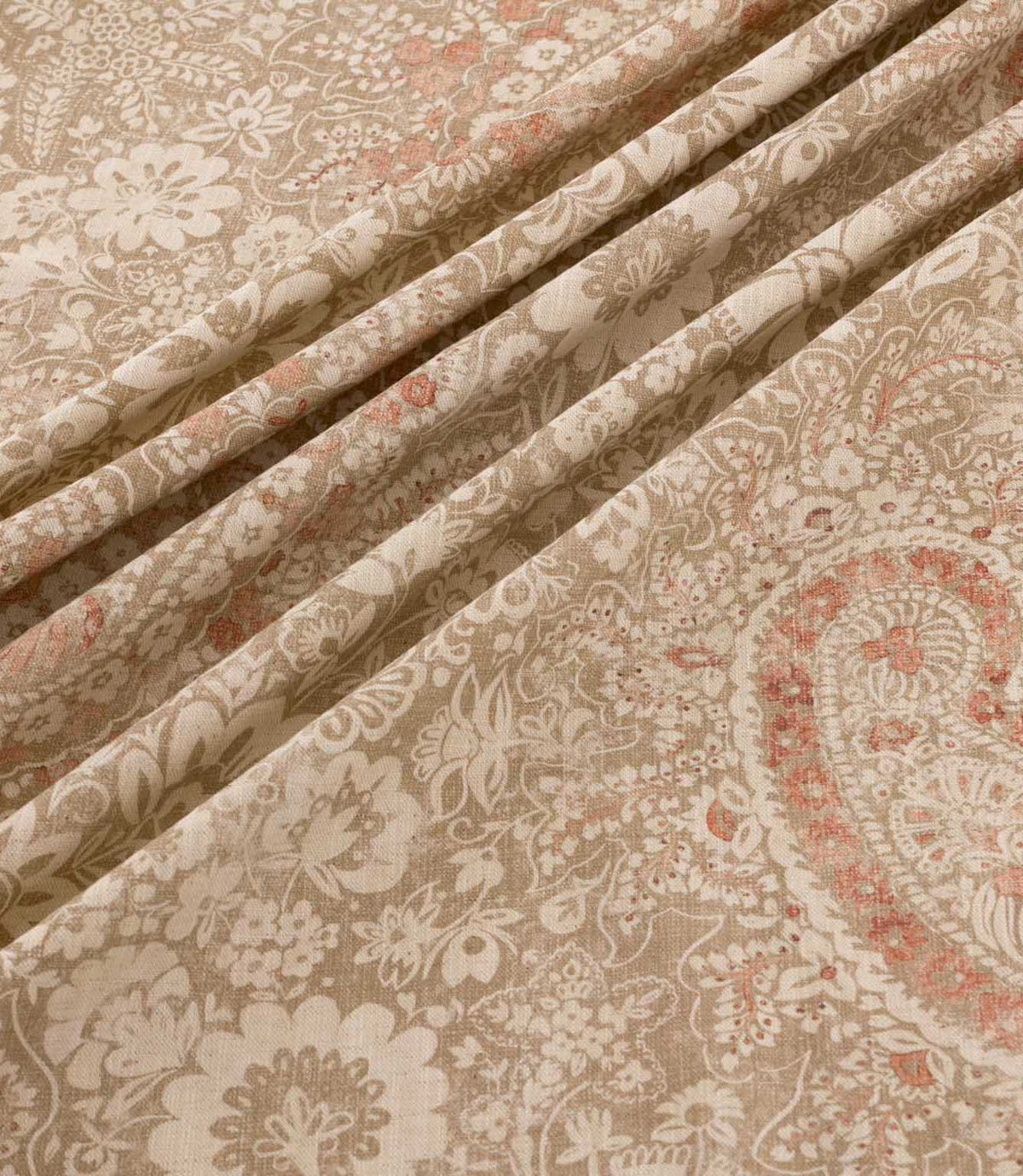 Southold Coralee fabric draped in soft diagonal folds, showcasing its detailed coral pink and cream paisley floral pattern, trailing botanical motifs, natural beige background and textured woven-look finish.