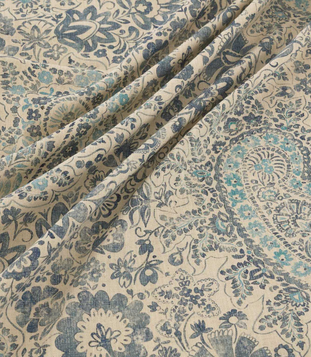 Southold Nautica fabric draped in soft diagonal folds, showcasing its intricate navy, teal and turquoise paisley floral pattern, delicate botanical detailing and textured cream background.
