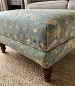 Decorative William Morris ottoman with floral, strawberry and bird pattern fabric.