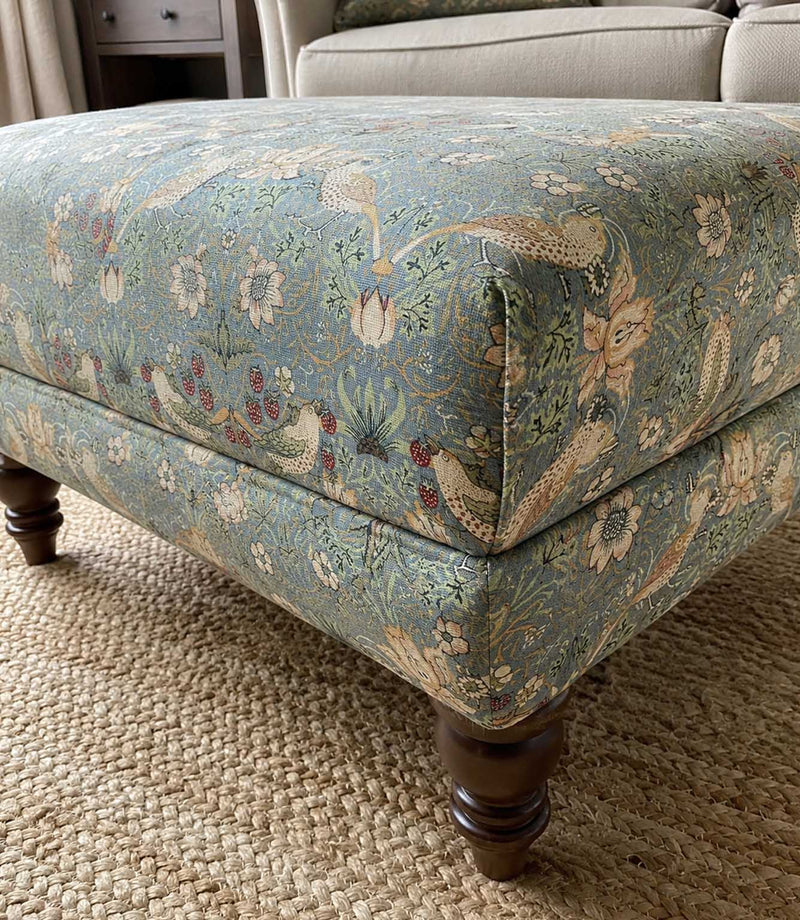 Decorative William Morris ottoman with floral, strawberry and bird pattern fabric.