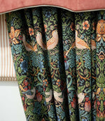 Strawberry Thief Tapestry Noir fabric made into gathered curtains, featuring birds, strawberries, flowers and dense green foliage on a dark background, styled beneath a rust pelmet.