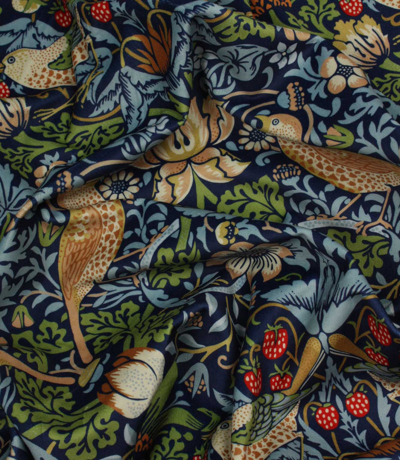Patterned William Morris velvet fabric with birds, flowers, strawberries and leaves on a dark blue background