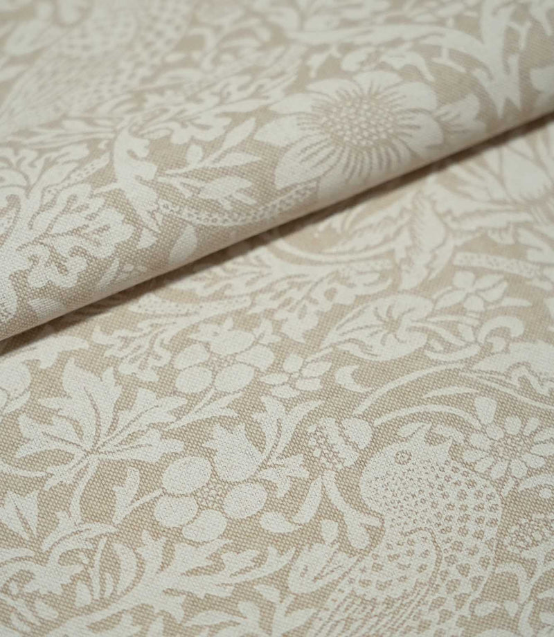 Folded Strawberry Thief Linen Look William Morris fabric in beige and off-white, highlighting the woven texture, bird motif, flowers and strawberries.
