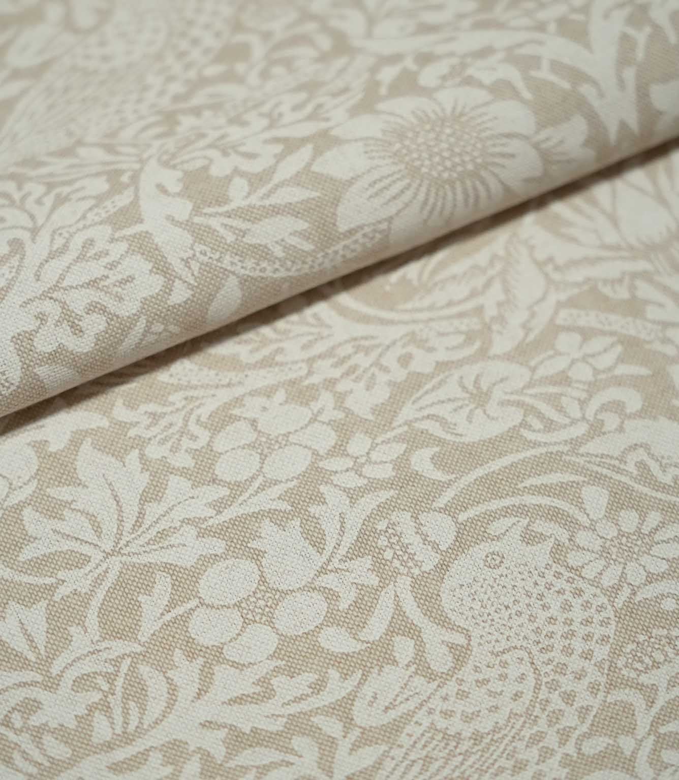 Folded Strawberry Thief Linen Look William Morris fabric in beige and off-white, highlighting the woven texture, bird motif, flowers and strawberries.