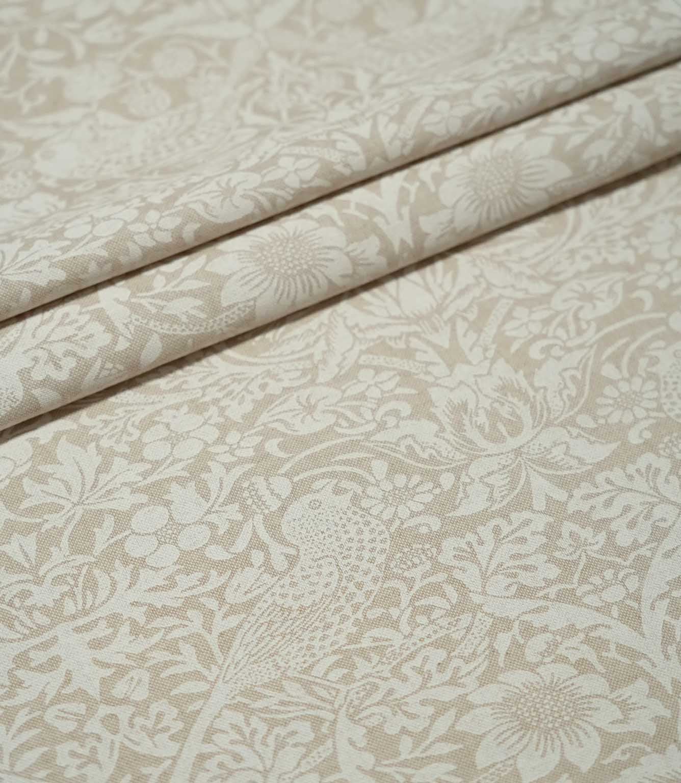 Beige and off-white Strawberry Thief Linen Look fabric arranged in soft folds, showing the repeating William Morris bird, strawberry and floral pattern.
