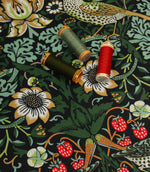 Black floral and bird print fabric shown with coordinating thread reels in green, mint and red tones.