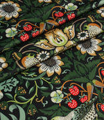 Folded botanical fabric with stylised flowers, birds and strawberries in rich green and cream colours.