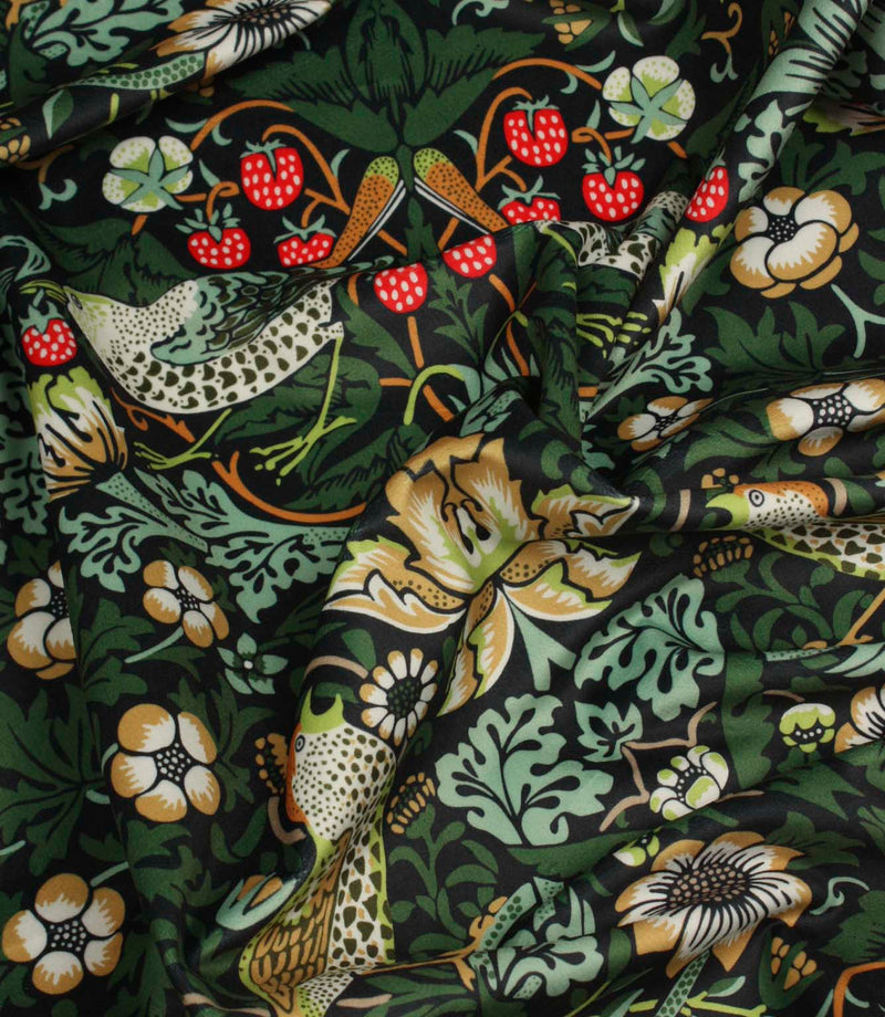 Draped Arts and Crafts style fabric featuring birds, foliage and floral motifs on a dark background.