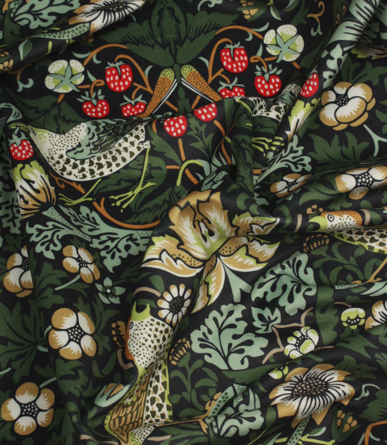 Draped Arts and Crafts style fabric featuring birds, foliage and floral motifs on a dark background.