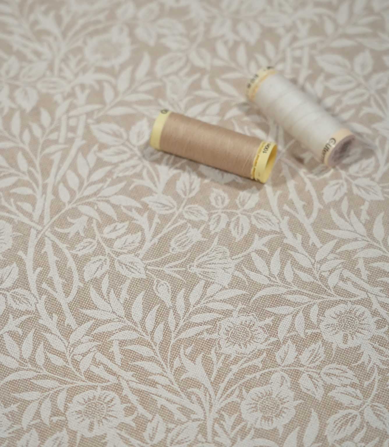 Close-up of Sweet Briar Linen Look fabric in cream and beige with sewing threads, showing the floral design and textured linen-look weave.