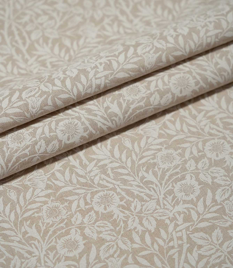 Sweet Briar Linen Look fabric arranged in neat folds, showing the cream floral and leafy design against a warm beige ground.