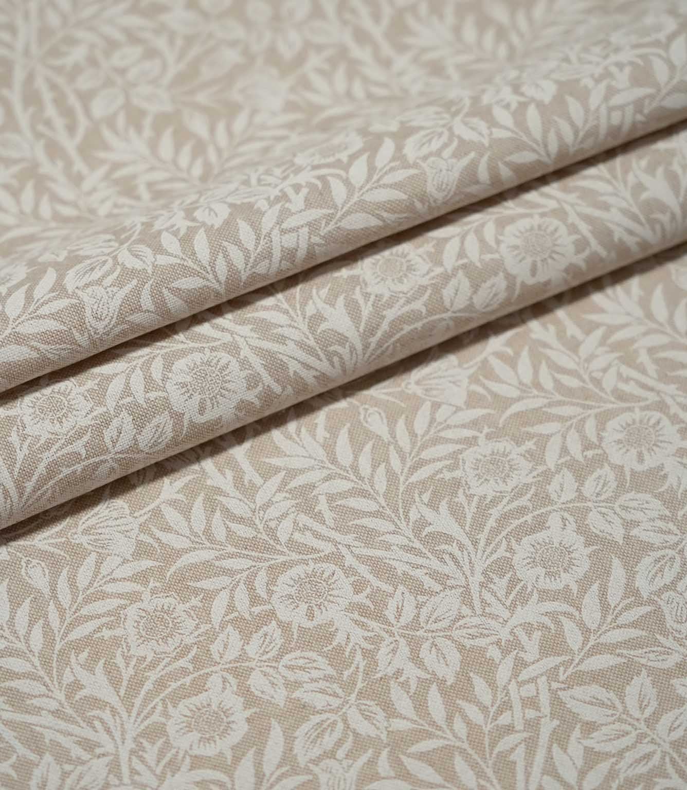 Sweet Briar Linen Look fabric arranged in neat folds, showing the cream floral and leafy design against a warm beige ground.