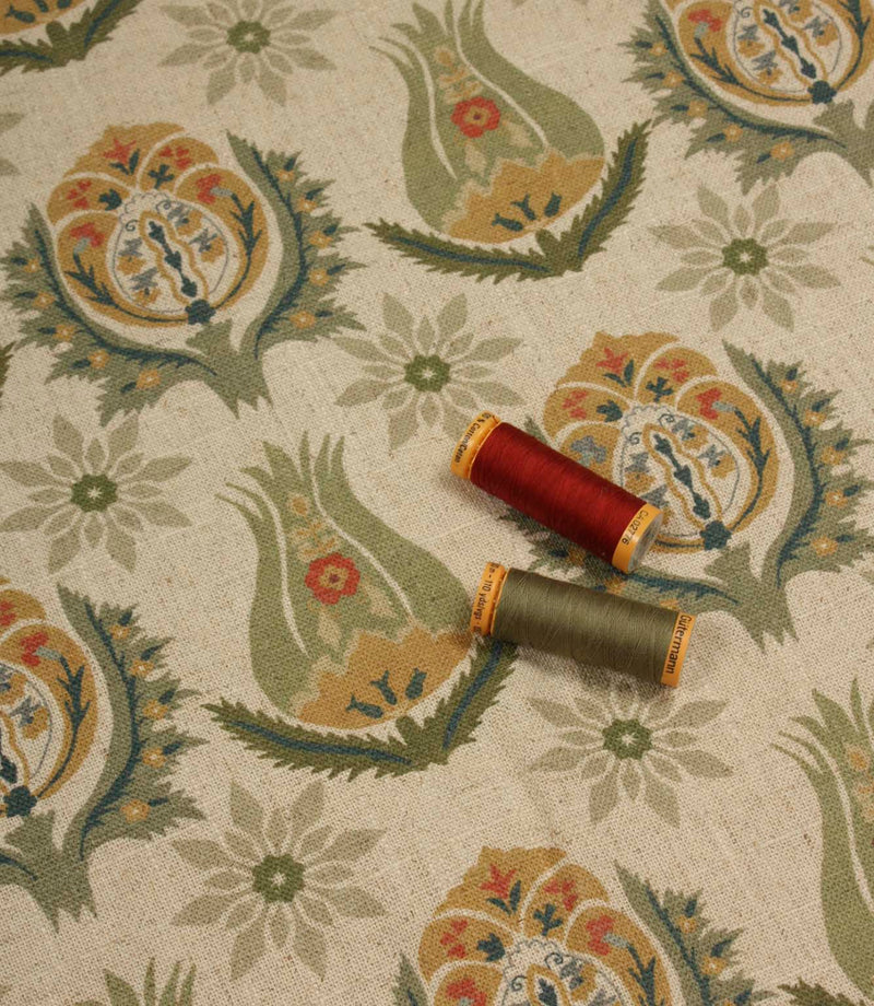 Natural linen-style floral fabric displayed with coordinating olive and red thread reels.